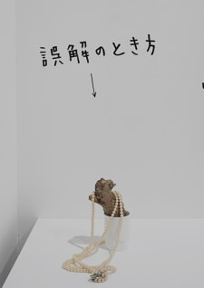 牛島光太郎の作品『組み合わせの方法』。日用品を組み合わせたモノと壁に油性ペンで言葉(文字)を書いた作品。