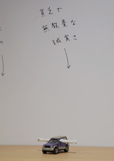 牛島光太郎の作品『組み合わせの方法』。日用品を組み合わせたモノと壁に油性ペンで言葉(文字)を書いた作品。