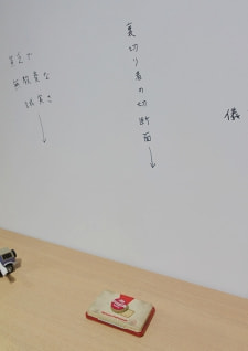 牛島光太郎の作品『組み合わせの方法』。日用品を組み合わせたモノと壁に油性ペンで言葉(文字)を書いた作品。