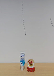 牛島光太郎の作品『組み合わせの方法』。日用品を組み合わせたモノと壁に油性ペンで言葉(文字)を書いた作品。